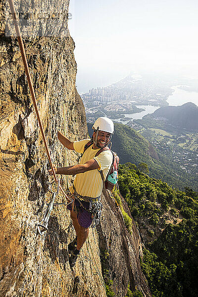 Schöner Blick auf männlichen Kletterer auf steilem felsigem Regenwaldberg
