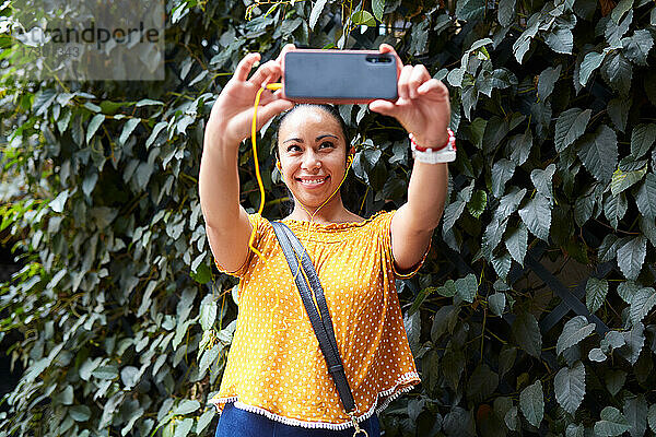 Junge Frau macht ein Selfie mit ihrem Smartphone auf der Straße