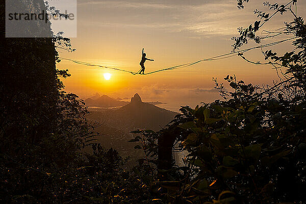 Schöner Blick auf männliche Highliner Silhouette auf orange Sonnenaufgang Berg