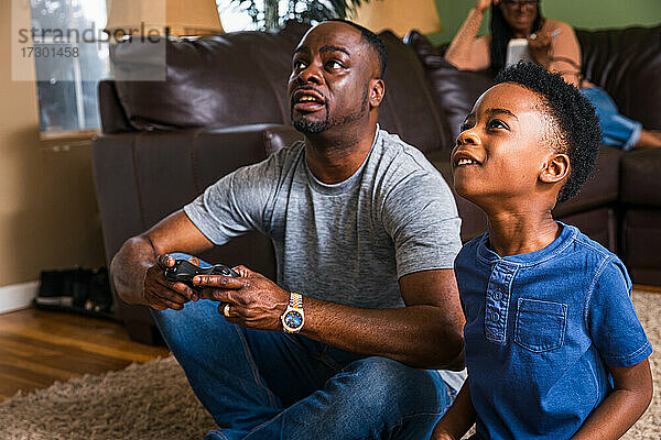 Vater und Sohn spielen ein Videospiel im heimischen Wohnzimmer