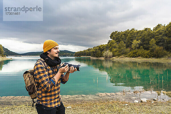 Lächelnder Tourist  der mit seiner Kamera in der Natur fotografiert