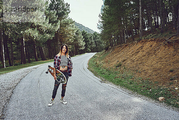Eine Frau mit einem Skateboard auf einer Bergstraße
