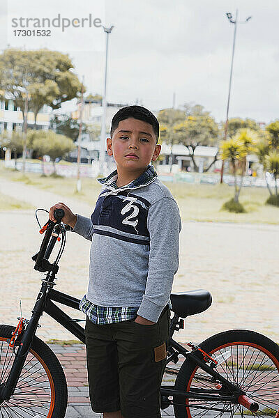 Ein Junge geht mit seinem Fahrrad spazieren.