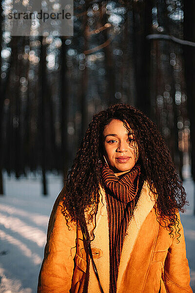 Porträt einer jungen Frau  die an einem sonnigen Tag im Winter im Park steht