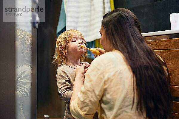 Eine Mutter bringt ihrem Sohn das Zähneputzen bei. Im Badezimmer.