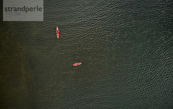 Draufsicht auf rote Boote mit Touristen  die auf dem dunklen Wasser eines Sees in Island schwimmen