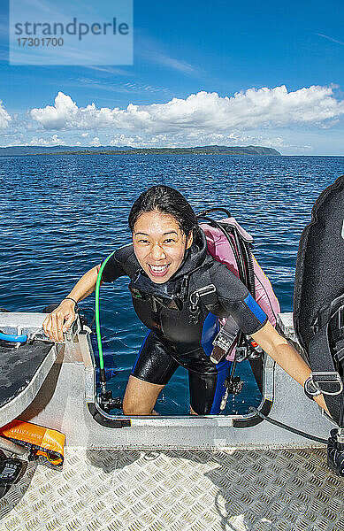 Taucher  der nach einem erfolgreichen Tauchgang in Raja Ampat wieder in sein Beiboot steigt