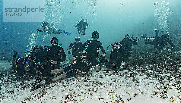 Eine Gruppe von Freunden posiert für die Kamera auf dem Meeresboden in Raja Ampat