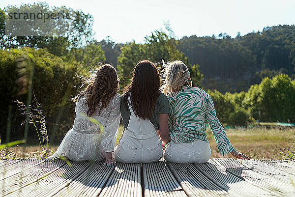 Drei unerkennbare Mädchen sitzen und genießen die Natur