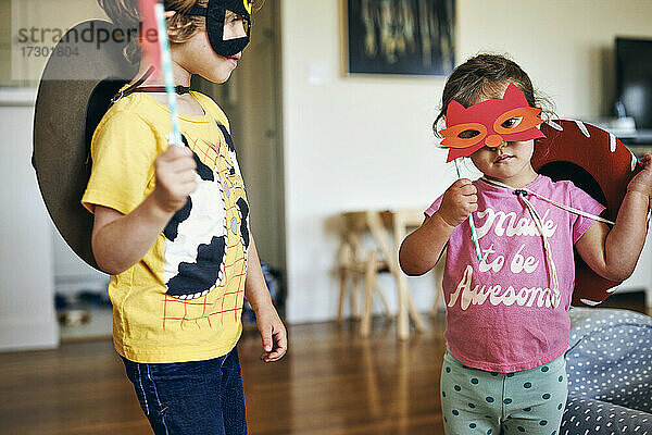 Bruder und Schwester tragen zu Hause Maskerade-Masken