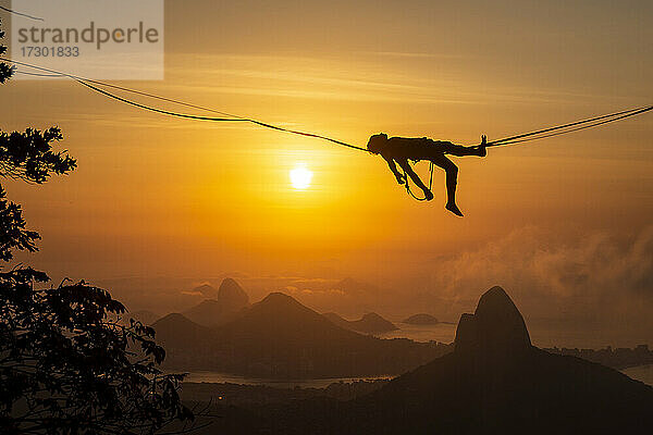 Schöner Blick auf die Silhouette eines männlichen Highliners  der auf einem Berg liegt