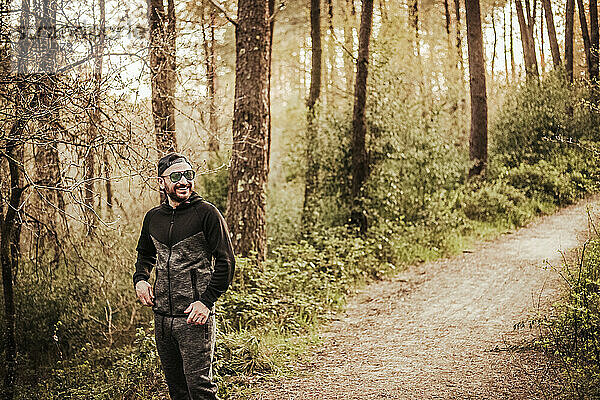 Mann mit Mütze und Sonnenbrille lächelnd in einem schönen Wald