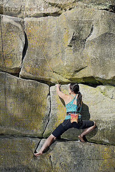 Frau klettert auf den Sandsteinfelsen am Harrison's Rock in England