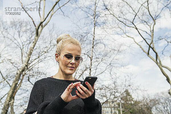 Erwachsene Frau benutzt Smartphone im Park