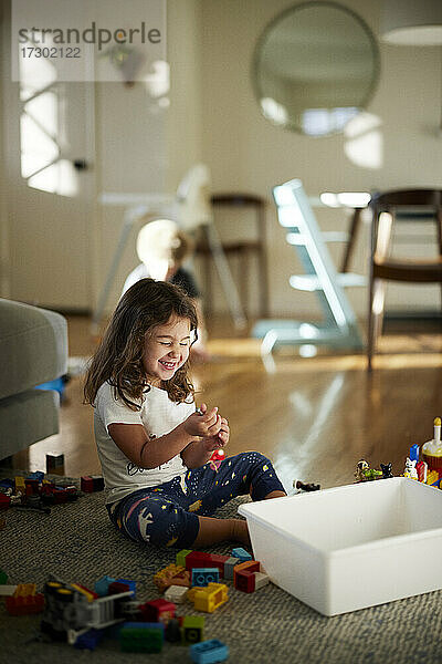 Nettes Mädchen lächelnd beim Spielen mit Spielzeug zu Hause