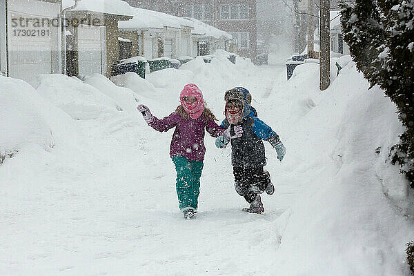 Zwei Kinder spielen während eines Schneesturms in der Gasse