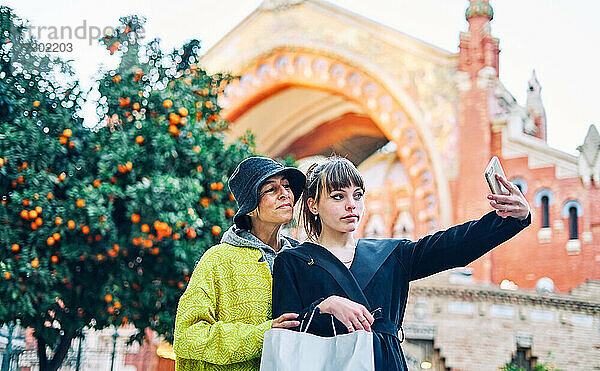 Mutter und Tochter beim Einkaufen  die ein Selfie auf der Straße in der Stadt machen