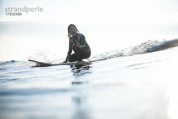 Asiatische Frau mit Spaß auf den Wellen während Sonnenaufgang Sommer Surf-Session