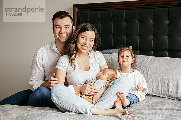 Glückliche lustige Familie mit zwei kleinen Kindern  einem Kleinkind und einem Neugeborenen  zu Hause