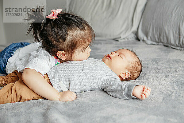 Cute Kleinkind ältere Schwester umarmt neugeborenen jüngeren Baby Bruder Junge.