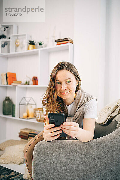 Hübsches Mädchen arbeitet am Telefon in einem Stuhl