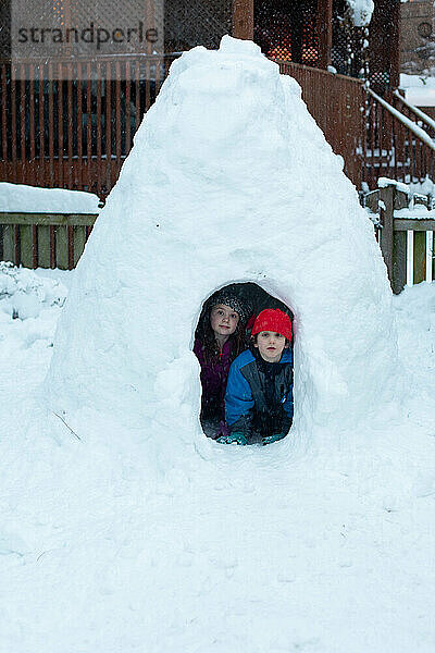 Zwei Kinder in einer Schneefestung im Winter