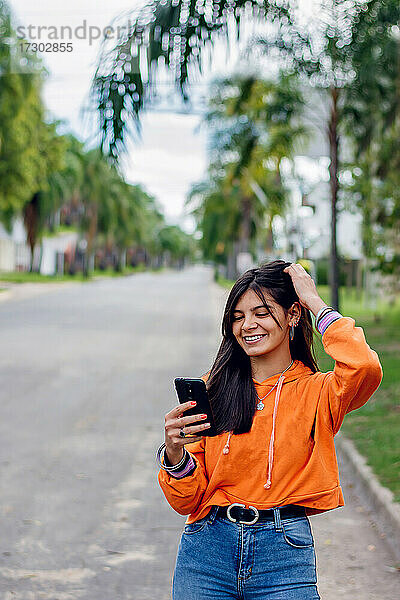 Glückliches hispanisches Teenager-Mädchen mit Blick auf ihr Smartphone