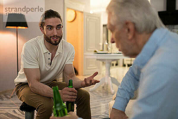 Junger Mann trinkt Bier und spricht mit seinem Großvater