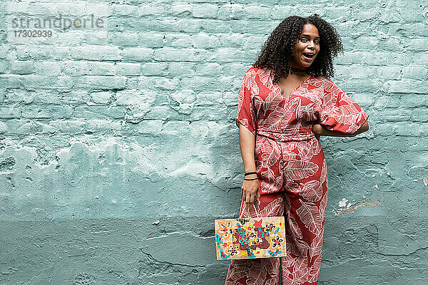 Modische Afroamerikanerin mit lockigem Haar  in einem roten Kleid