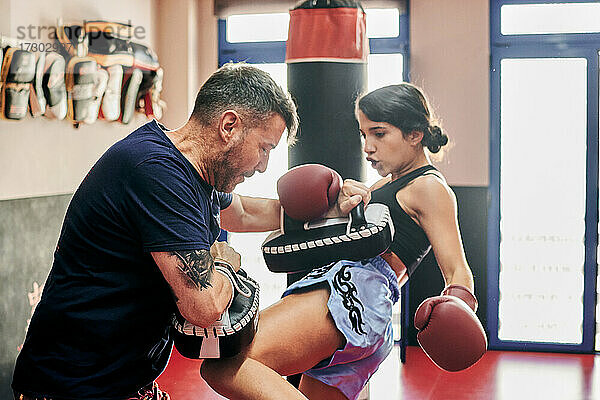 Junge Frau trainiert mit ihrem Muay Thai-Trainer in einem Fitnessstudio
