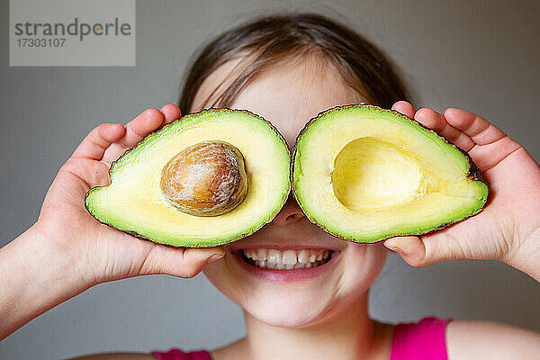 Porträt eines jungen lächelnden Mädchens mit reifer köstlicher Avocado