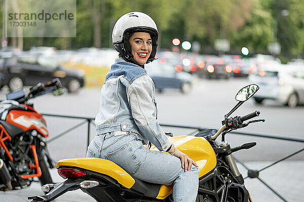 Rechte Seitenaufnahme einer jungen Frau auf einem gelben Motorrad