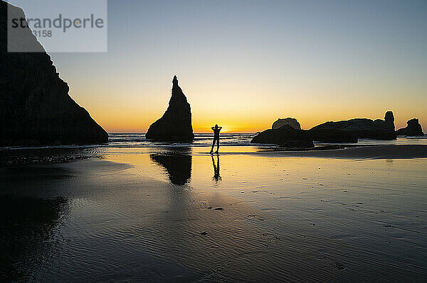 Sonnenuntergang an der Küste mit silhouettierten Wanderer
