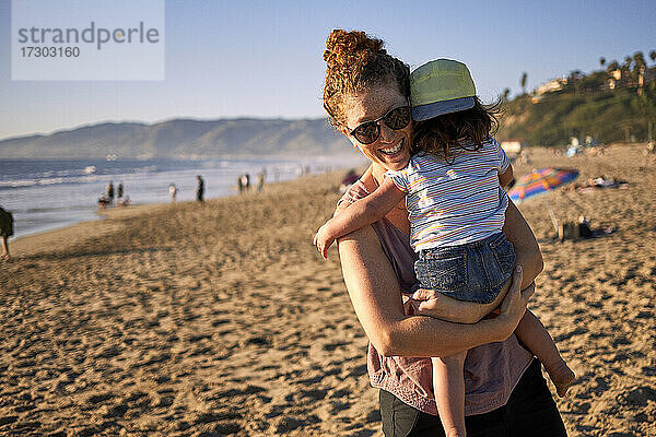 Lächelnde Mutter mit Tochter am Strand während des Wochenendes