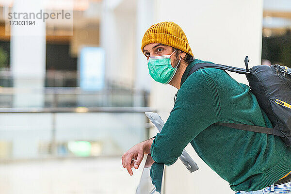 Moderner spanischer Mann mit grüner Schutzmaske im Einkaufszentrum
