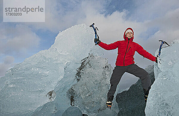 Frau klettert mit Eispickel auf Eisberg an der Südküste von Island