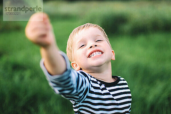 Kleiner Junge lächelnd in einem großen Feld auf dem Lande