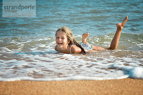 Lachendes Mädchen beim Schwimmen in den Wellen am Strand