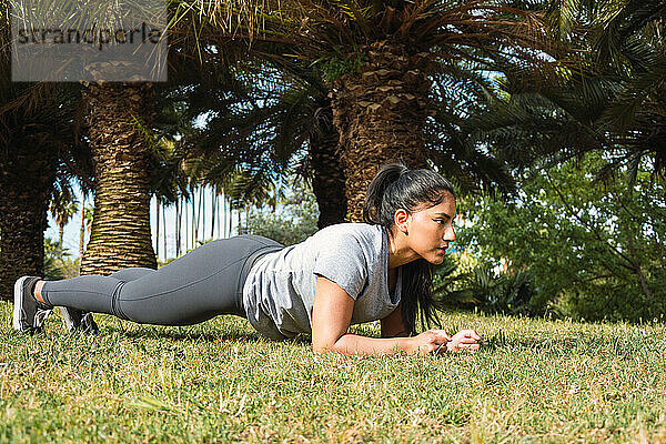 junges Mädchen trainiert Bauchmuskeln auf dem Rasen im Park