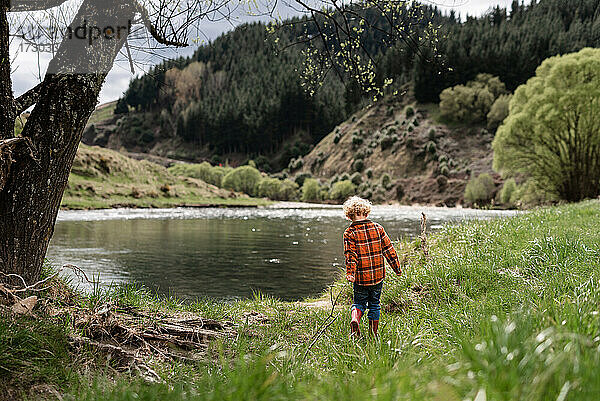 Kleines Kind mit Stock in der Nähe von Wasser in Neuseeland