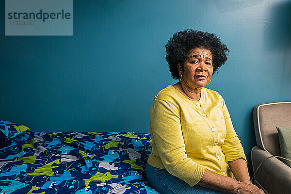 Porträt einer ernsten älteren Frau  die zu Hause im Schlafzimmer sitzt