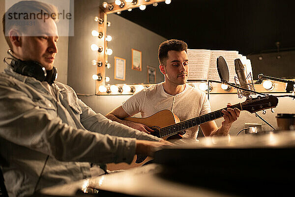 Männliche Musiker spielen Instrumente  während sie im Studio zusammen Musik machen