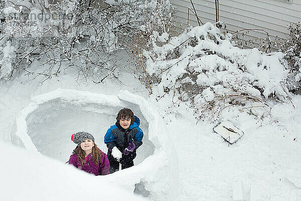 Zwei Kinder bauen im Winter eine Schneefestung