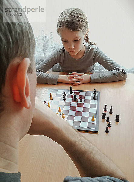 Mädchen spielt Schach am Tisch zu Hause