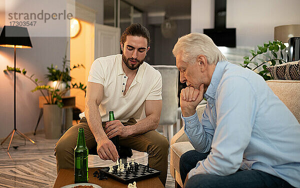 Ältere und junge Männer mit Bier spielen Schach