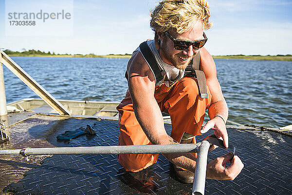 Junger Mann bei der Arbeit auf dem Wasser in der Aquakultur Austernzucht