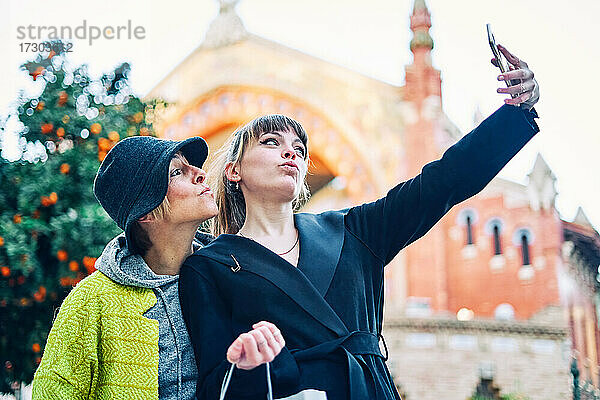 Mutter und Tochter beim Einkaufen  die ein Selfie auf der Straße in der Stadt machen