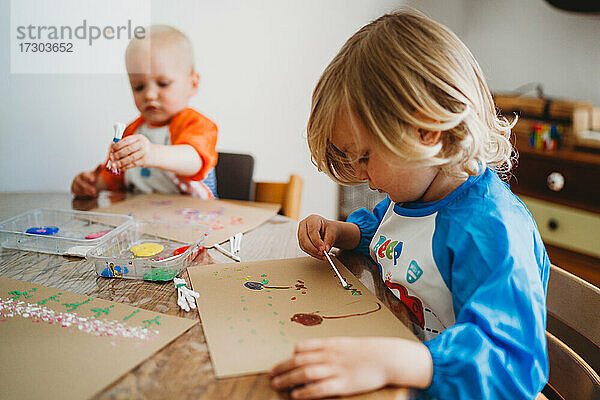 Kleine Kinder malen mit vielen bunten Farben zu Hause  wenn sie eingesperrt sind
