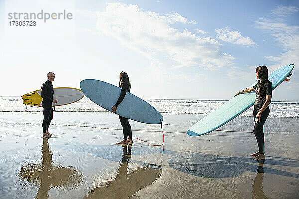 Gruppe von Surferfreunden beim Surfen im Sommer bei Sonnenaufgang