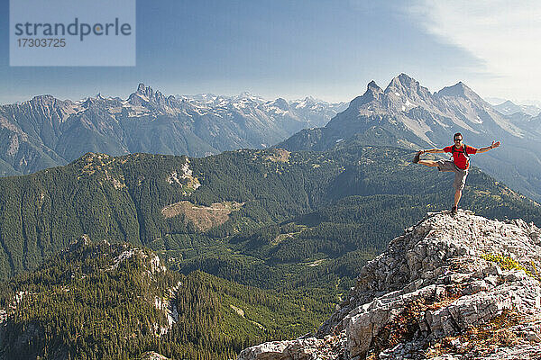 Trailrunner balanciert und streckt sich auf einem Berggipfel.